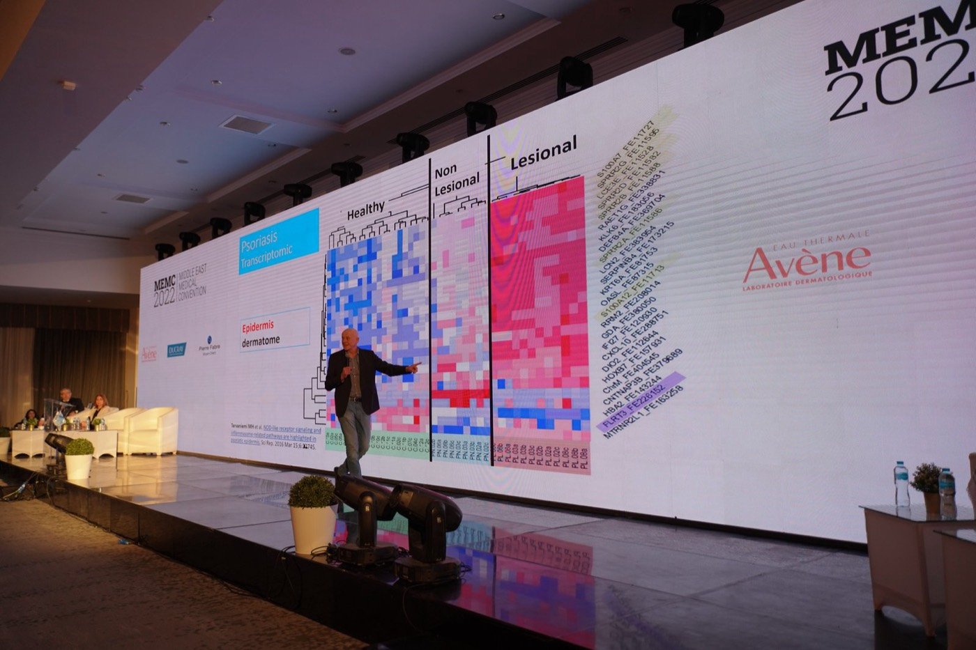 Speaker on stage in front of a full-width LED wall at a medical convention