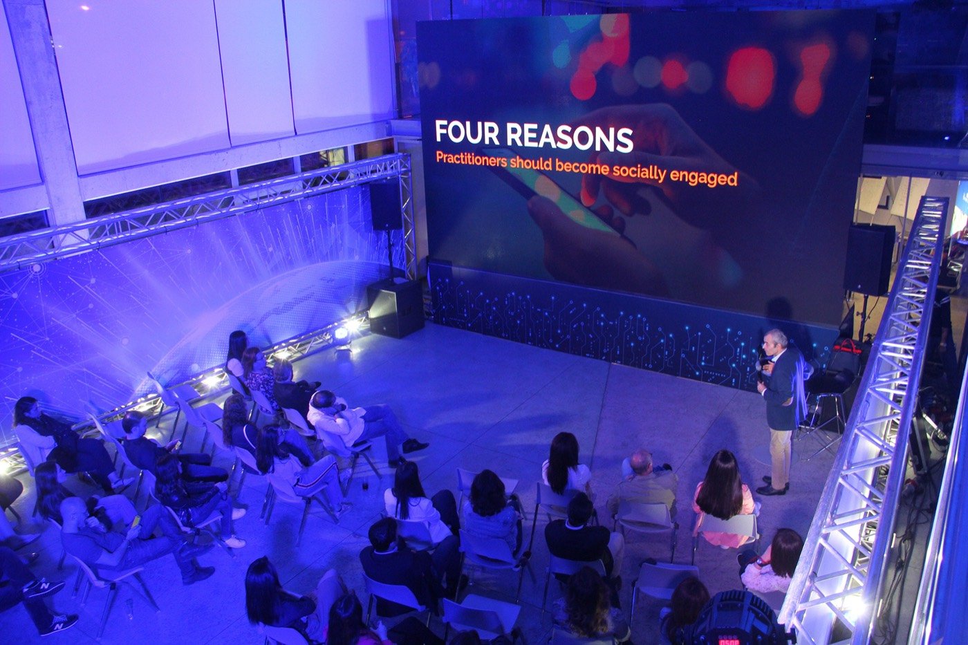 Speaker beneath a large LED screen at the Pierre Fabre Academy launch